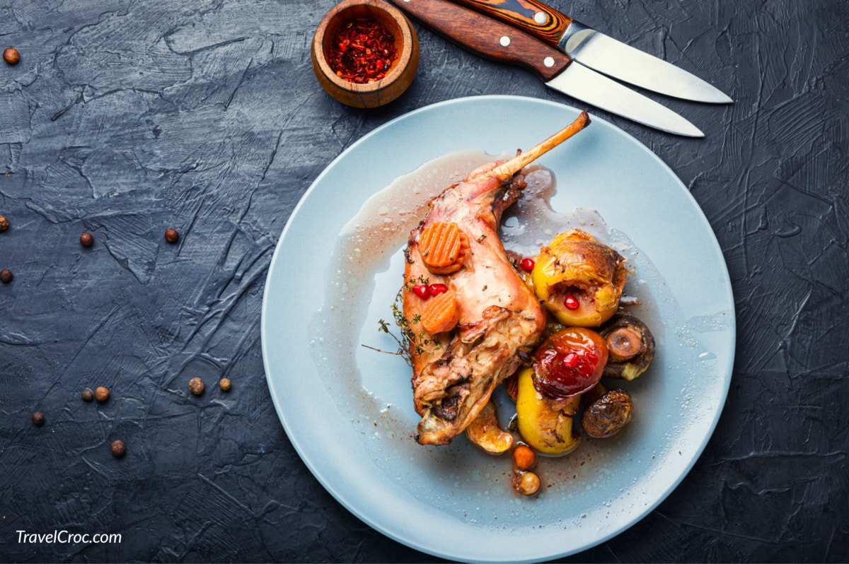 Baked rabbit leg with apples, carrots and mushrooms.
