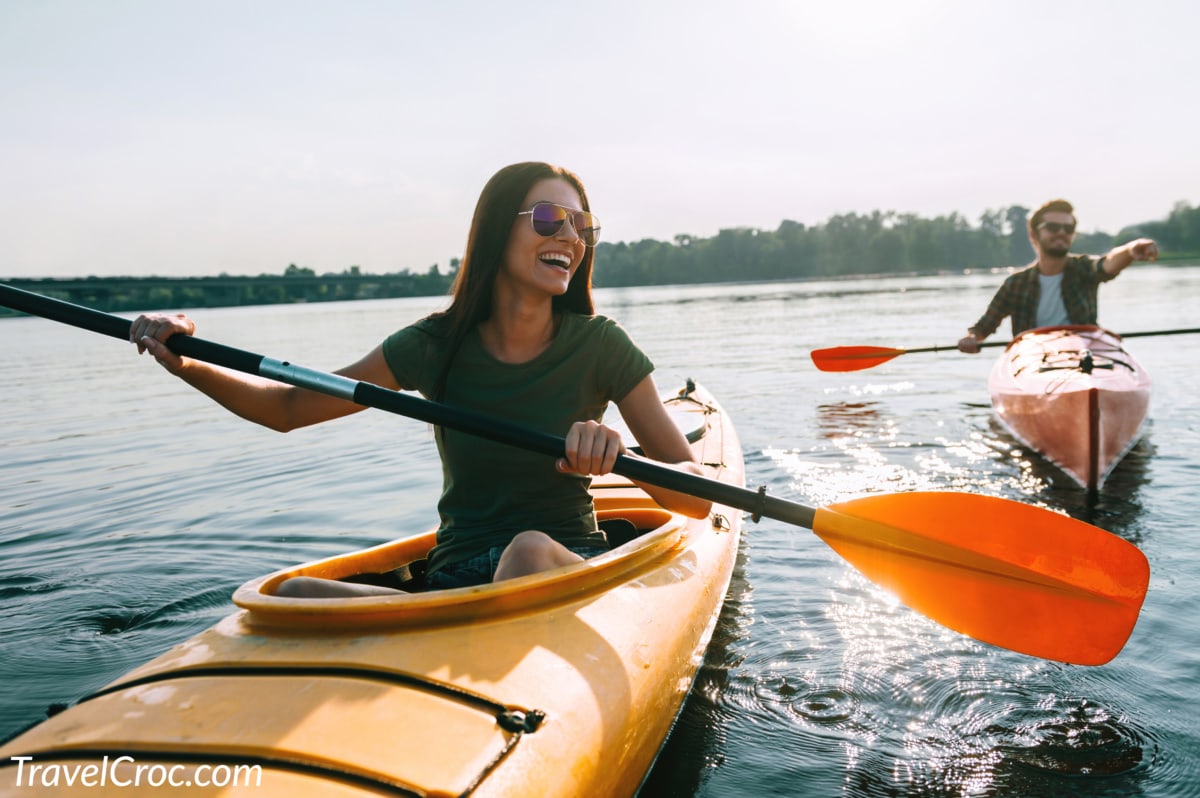 Beautiful young couple kayaking on lake together and smiling.