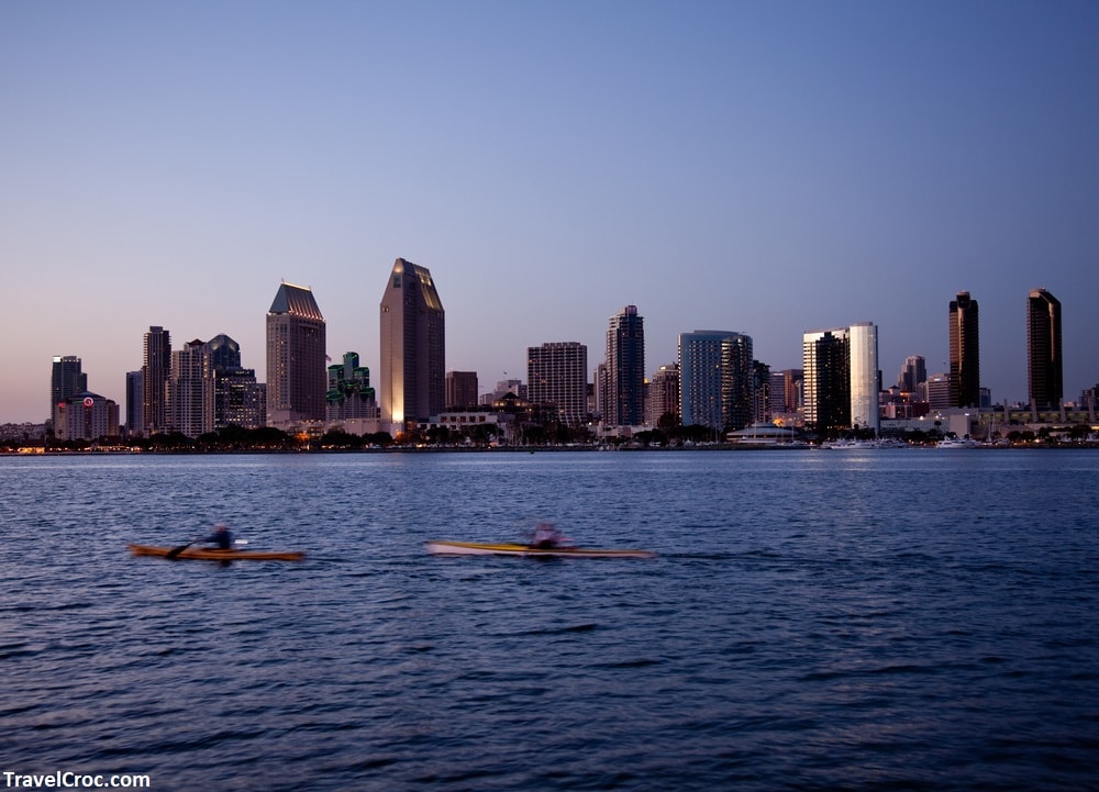 Sun setting lights up the buildings on San Diego seafront with kayaks and canoes - Kayaking Mission Bay