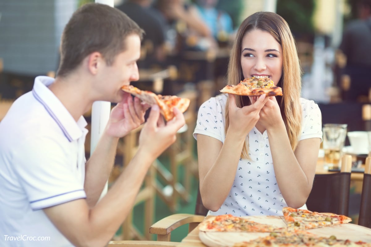 Young couple sitting in a restaurant eating pizza