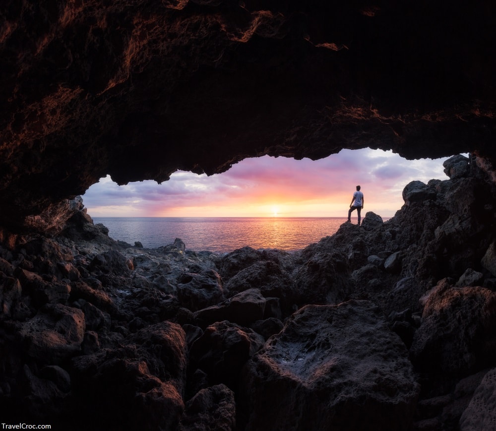 Boy watching a sunset through a cave at Le Souffleur in Saint-Leu, Reunion Island