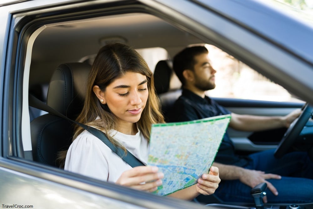 Seattle to Yellowstone National Park Distance - Beautiful hispanic woman looking at the map while taking a road trip with her boyfriend in the car