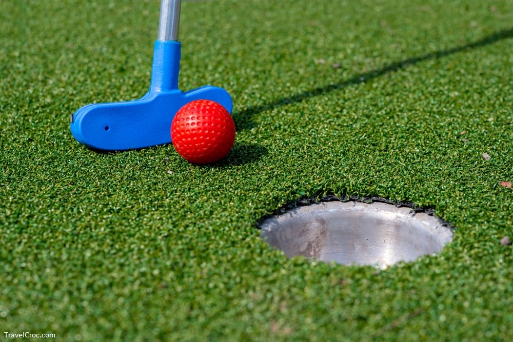Kid friendly things to do in Rocky Mount, NC -Detail of minigolf club and red golf ball aiming into the hole.
