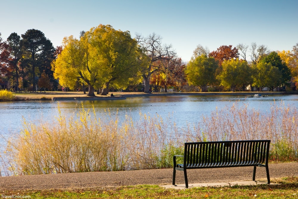 Empty bench by lake with Fall trees - Washington Park - Denver, Colorado - Best Time To Visit Denver