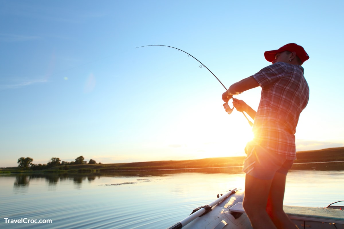 Man fishing on lake at sunset