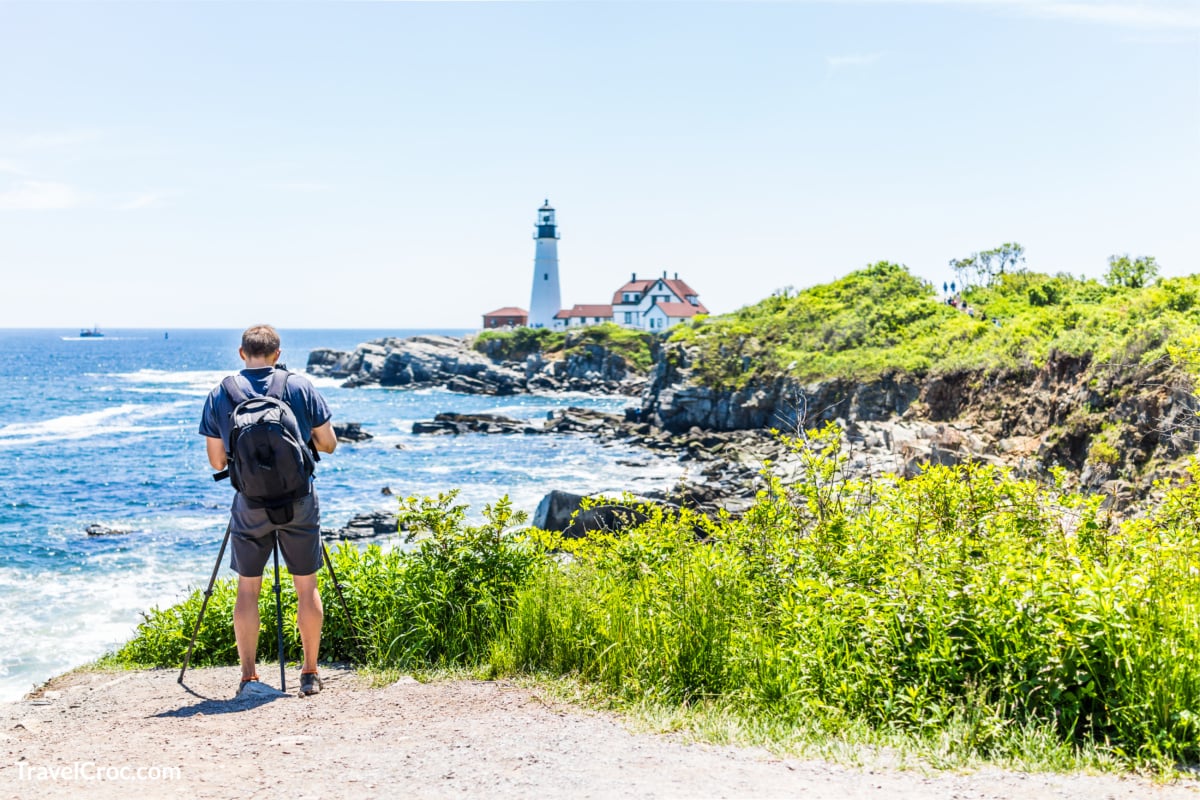 Man hiking in Portland Maine and viewing the lighthouse.