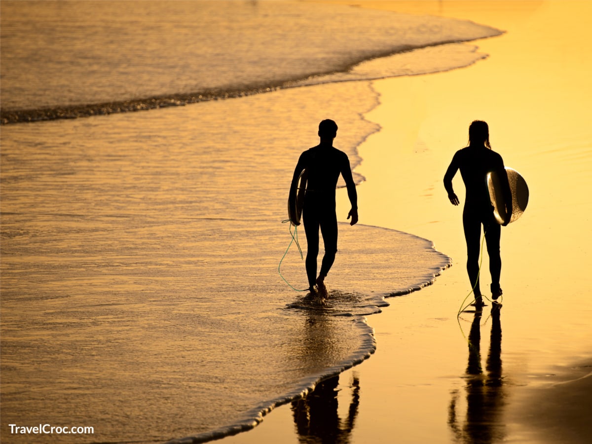 Surfers walking by beach after sunset