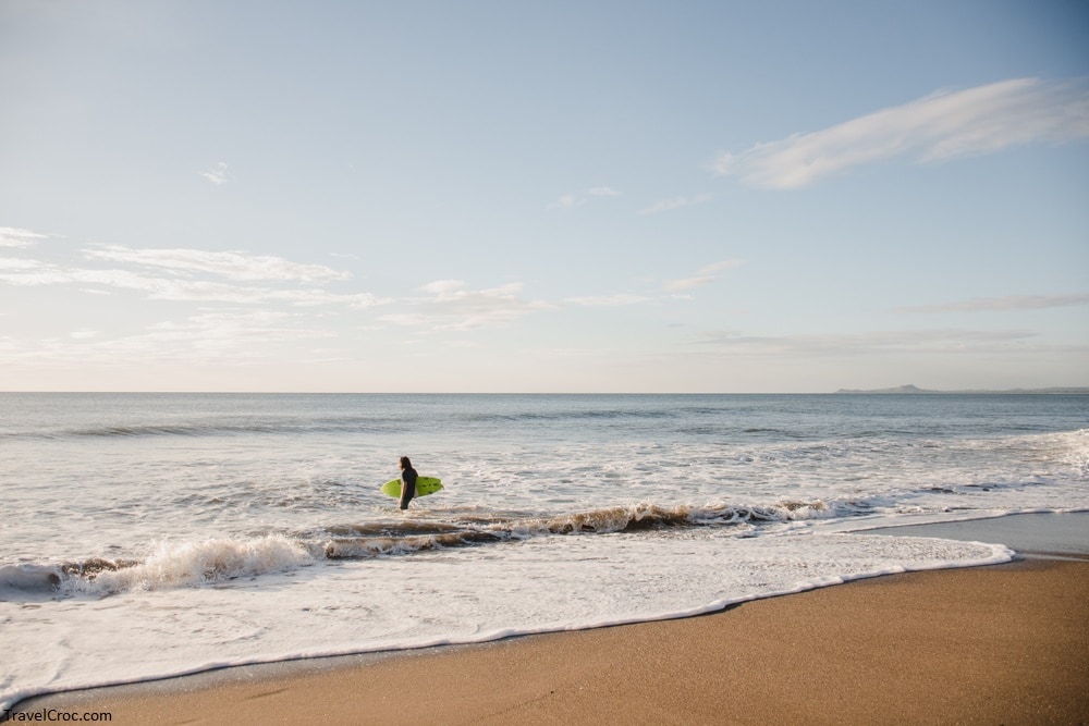 A surfer stands in the Pacific Ocean looking for waves to surf at El Transito, Nicaragua.