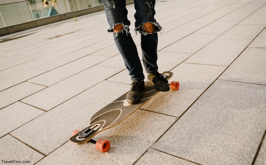 Denver Colorado Skateparks - White man wearing jeans skateboarding on parking outdoors