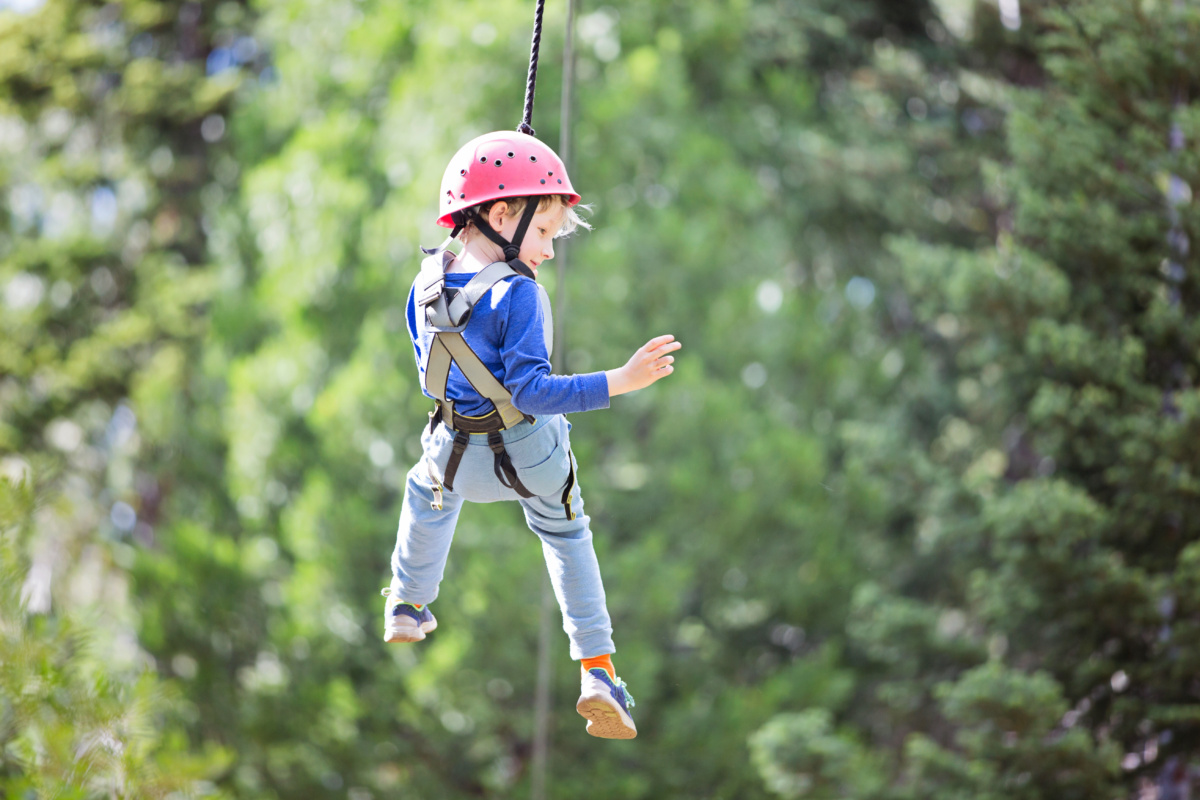 Child hanging off harness at adventure park